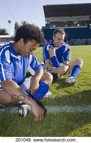 Two soccer players sitting on a soccer field, laughing View Large Photo Image Stock Photo - Two soccer players sitting on a soccer field, laughing. Fotosearch