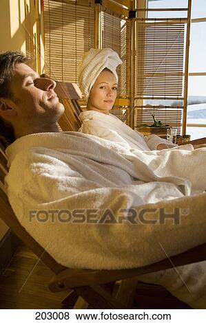 Couple reclining on chairs in bathrobes View Large Photo Image Stock Photo - Couple reclining on chairs in bathrobes. Fotosearch