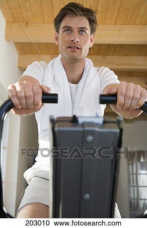 Man with towel around his neck using exercise equipment View Large Photo Image Stock Image - Man with towel around his neck using exercise equipment. Fotosearch