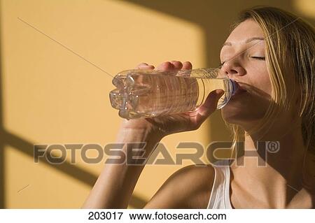 Young woman drinking water from plastic bottle View Large Photo Image Stock Photo - Young woman drinking water from plastic bottle. Fotosearch