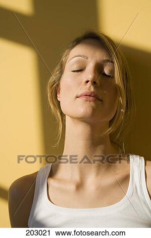 Young woman standing in sunlight with eyes closed View Large Photo Image Stock Image - Young woman standing in sunlight with eyes closed. Fotosearch
