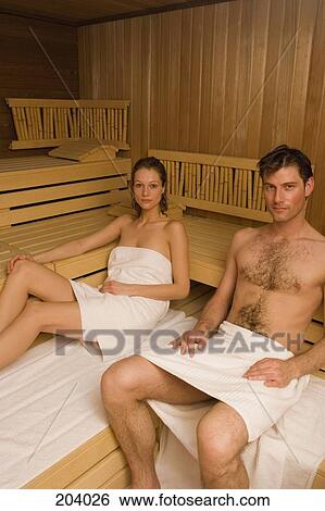 Stock Photograph - Couple wrapped in towels and sitting in sauna. Fotosearch