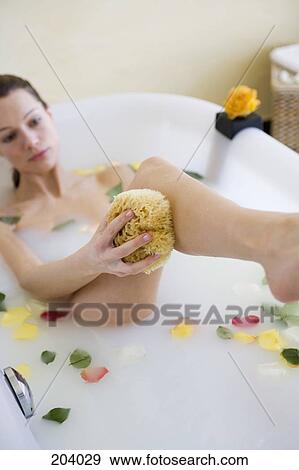 Young woman holding sponge in bathtub View Large Photo Image Stock Photo - Young woman holding sponge in bathtub. Fotosearch