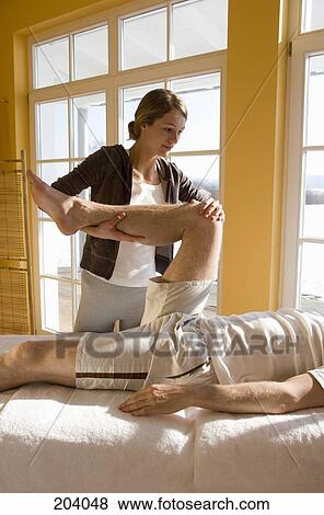 Young woman massaging man's leg View Large Photo Image Stock Photo - Young woman massaging man's leg. Fotosearch
