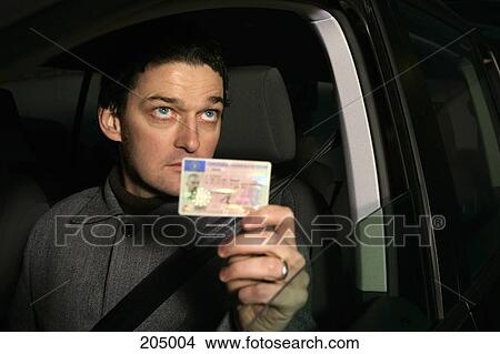 Man sitting in car and holding his ID card View Large Photo Image Picture - Man sitting in car and holding his ID card. Fotosearch