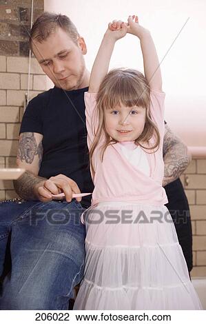 Stock Image - Father helping his daughter get dressed. Fotosearch