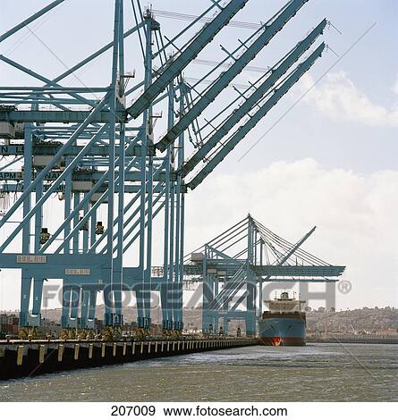 Cargo ship under blue cranes on commercial dock View Large Photo Image Stock Photo - Cargo ship under blue cranes on commercial dock. Fotosearch