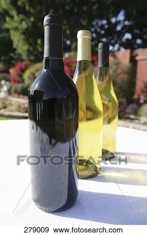 Bottles of wine on table in garden View Large Photo Image Stock Photo - Bottles of wine on table in garden. Fotosearch