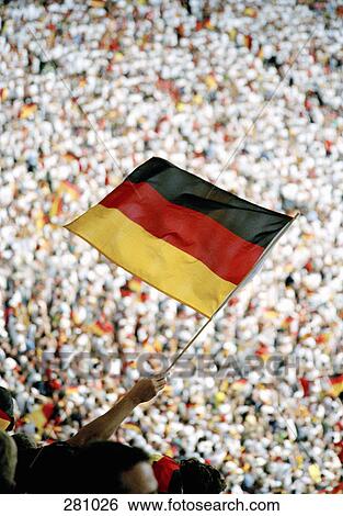 Spectator holding German flag at sports event View Large Photo Image Stock Photograph - Spectator holding German flag at sports event. Fotosearch