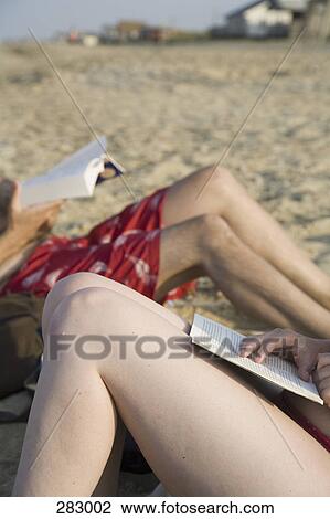 Two people sitting on beach sunbathing and reading View Large Photo Image Stock Image - Two people sitting on beach sunbathing and reading. Fotosearch