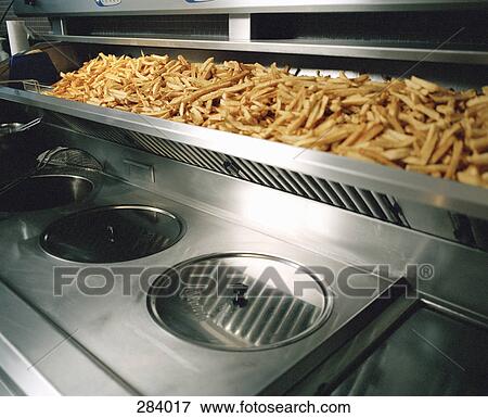 Stock Photo - French fries on shelf above deep fryer. Fotosearch