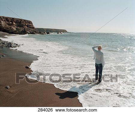 Woman standing at the edge of the sea View Large Photo Image Stock Photograph - Woman standing at the edge of the sea. Fotosearch