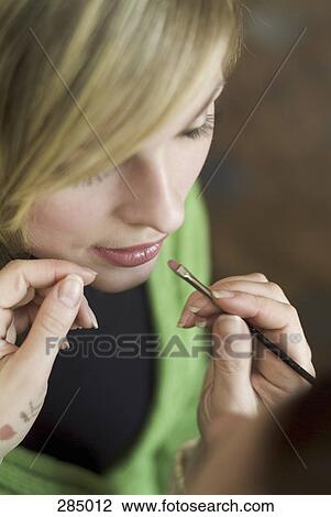 Stock Image - Makeup artist applying lipstick to a model. Fotosearch