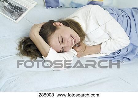 Young woman lying on bed and laughing View Large Photo Image Stock Photo - Young woman lying on bed and laughing. Fotosearch
