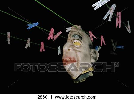 Stock Image - Rubber monster mask hanging on clothesline. Fotosearch