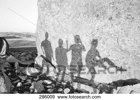 Stock Photo - Shadow of four figures on rock. Fotosearch