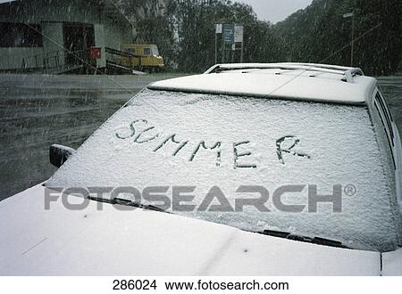 Picture - ‘Summer’ written on windshield of car covered in snow. Fotosearch