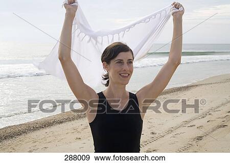 Woman holding sarong above head on beach View Large Photo Image Stock Photo - Woman holding sarong above head on beach. Fotosearch