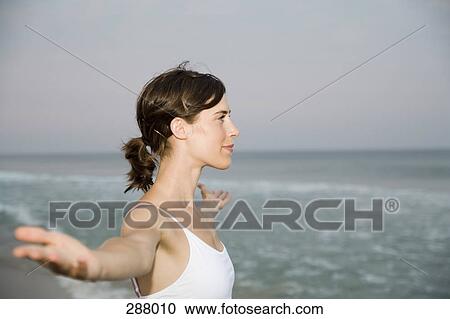 Woman standing on beach with arms outstretched View Large Photo Image Stock Image - Woman standing on beach with arms outstretched. Fotosearch