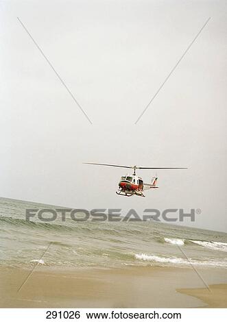 Rescue helicopter flying over beach View Large Photo Image Stock Photograph - Rescue helicopter flying over beach. Fotosearch