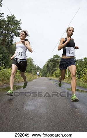 Stock Photography - Two women running on road in sports race. Fotosearch