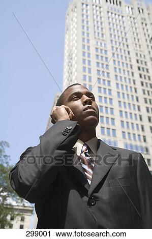 Businessman standing in financial district using mobile phone View Large Photo Image Stock Image - Businessman standing in financial district using mobile phone. Fotosearch