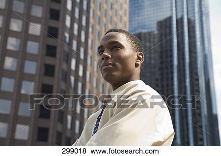 Stock Photo - Young businessman in financial district looking away. Fotosearch