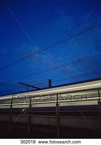 Train traveling across bright at night View Large Photo Image Stock Photo - Train traveling across bright at night. Fotosearch