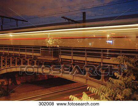 Train traveling over bridge at night View Large Photo Image Stock Photo - Train traveling over bridge at night. Fotosearch