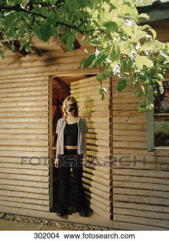 Woman stood at entrance of cabin wearing mask View Large Photo Image Picture - Woman stood at entrance of cabin wearing mask. Fotosearch