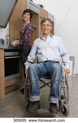 Man sitting in wheelchair and woman standing behind in domestic kitchen View Large Photo Image Stock Photography - Man sitting in wheelchair and woman standing behind in domestic kitchen. Fotosearch