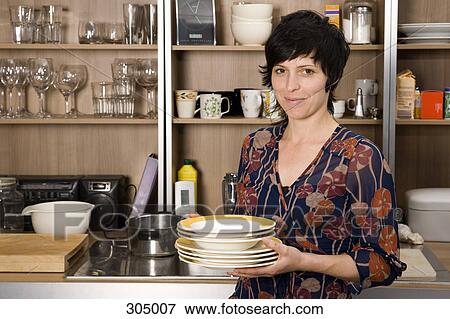 Woman holding plates in kitchen View Large Photo Image Stock Photo - Woman holding plates in kitchen. Fotosearch