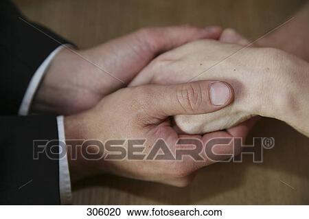 Stock Image - Close-up of couple holding hands. Fotosearch
