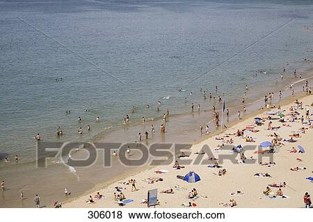 Stock Photo - People swimming in sea and sunbathing on beach. Fotosearch