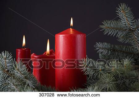 Stock Photo - Three red candles among pine branches. Fotosearch