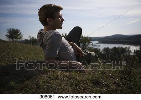 Man lying on grass and looking at view View Large Photo Image Stock Image - Man lying on grass and looking at view. Fotosearch