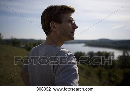 Man standing on hill and looking at view View Large Photo Image Stock Image - Man standing on hill and looking at view. Fotosearch