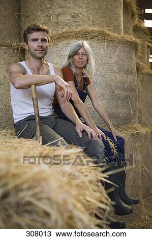 Two workers sitting on bale of hay in a barn View Large Photo Image Stock Image - Two workers sitting on bale of hay in a barn. Fotosearch
