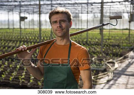 Worker carrying hoe in greenhouse View Large Photo Image Stock Photo - Worker carrying hoe in greenhouse. Fotosearch