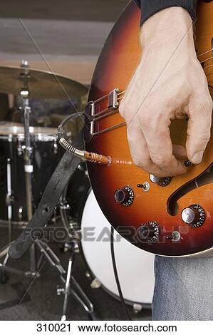Stock Image - Close-up of guitarist tuning guitar. Fotosearch