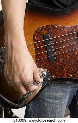 Stock Photo - Guitarist tuning guitar. Fotosearch