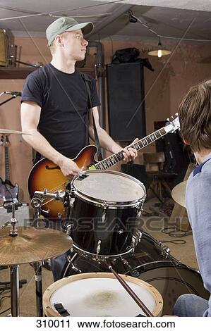 Two men practicing the drums and guitar View Large Photo Image Stock Image - Two men practicing the drums and guitar. Fotosearch