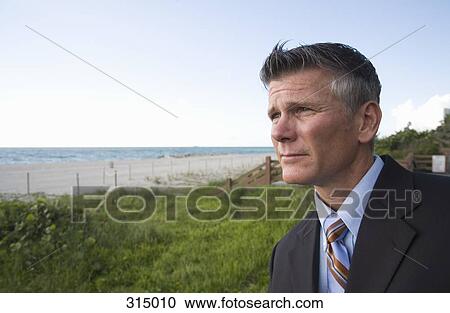 Businessman at the beach and looking at view View Large Photo Image Stock Image - Businessman at the beach and looking at view. Fotosearch
