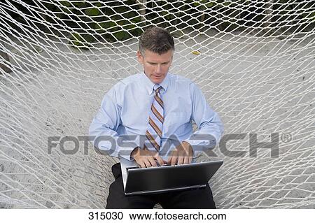 Businessman working on laptop, sitting in hammock View Large Photo Image Stock Image - Businessman working on laptop, sitting in hammock. Fotosearch