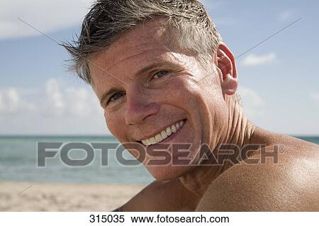 Man sitting on the beach and smiling View Large Photo Image Stock Photography - Man sitting on the beach and smiling. Fotosearch