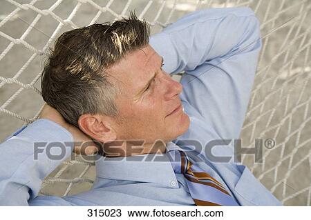 Mature businessman lying down on hammock View Large Photo Image Stock Image - Mature businessman lying down on hammock. Fotosearch