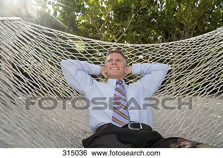 Mature businessman lying down on hammock View Large Photo Image Stock Photograph - Mature businessman lying down on hammock. Fotosearch
