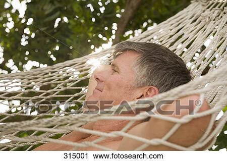 Stock Image - Mature man lying down on hammock. Fotosearch