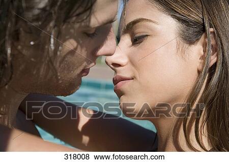 Young couple about to kiss by swimming pool View Large Photo Image Stock Photo - Young couple about to kiss by swimming pool. Fotosearch