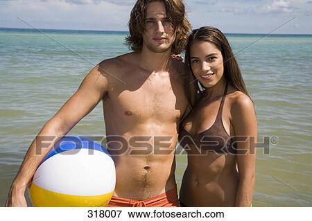 Stock Photo - Young couple embracing in front of the sea. Fotosearch